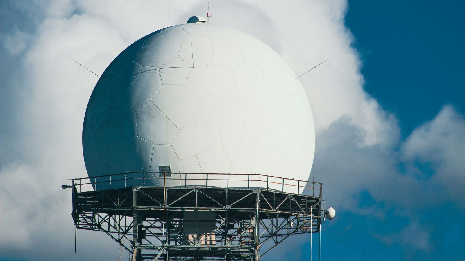 A white radar dome mounted on a ship's steel mast structure