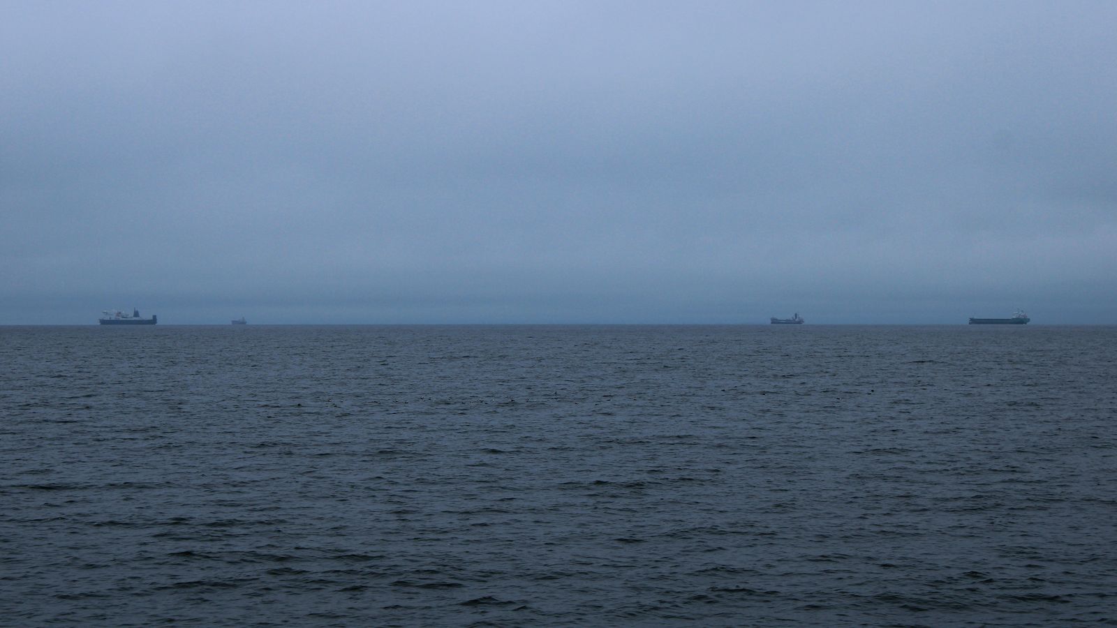 Several ships barely visible on a dark, overcast sea