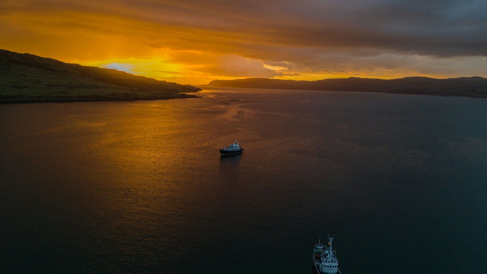 Two vessels lying at anchor on calm water at sunset